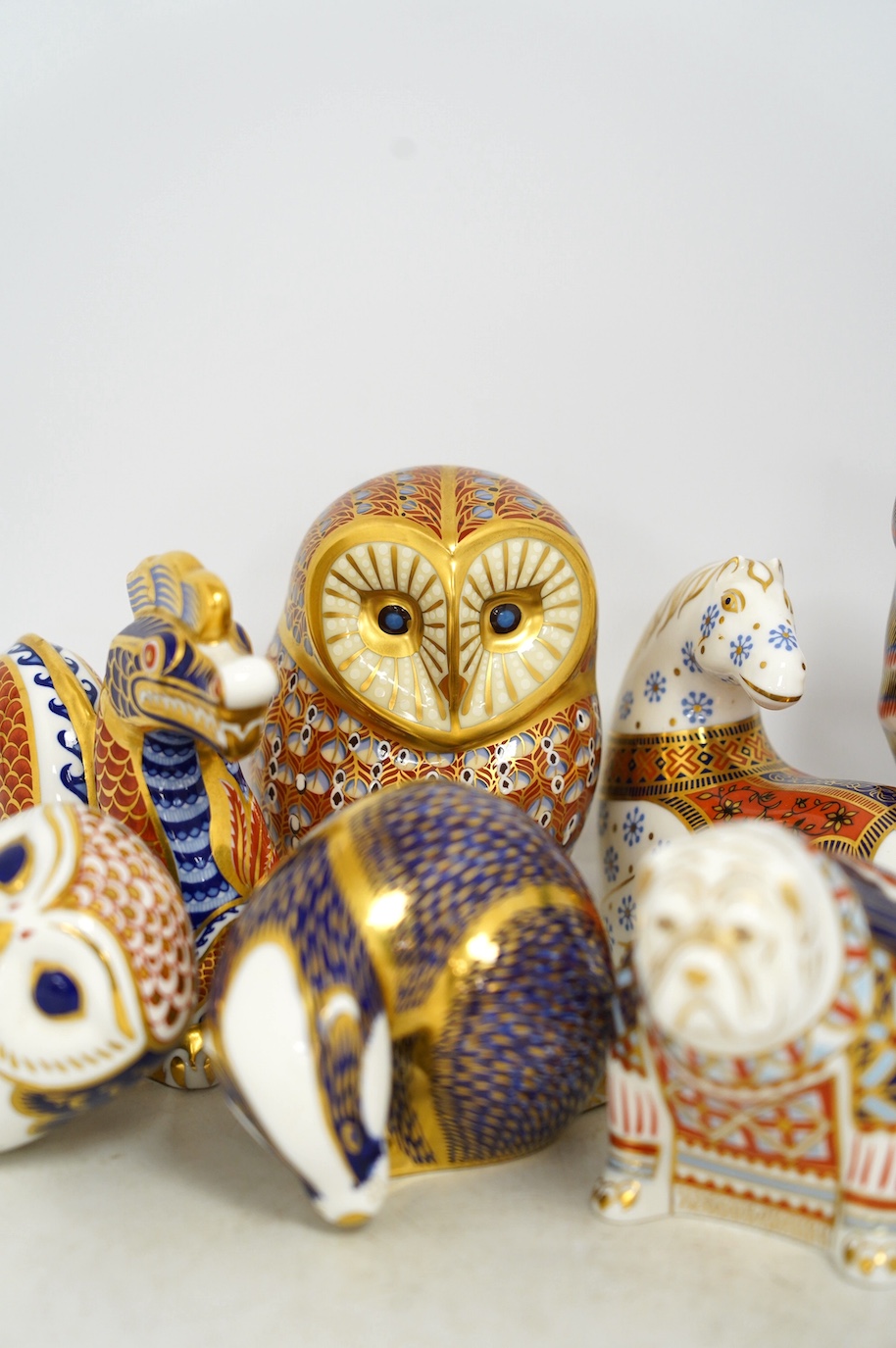 Eight Royal Crown Derby porcelain paperweights in the form of animals including a cat, badger and owl, largest 13.5cm high. Condition - good